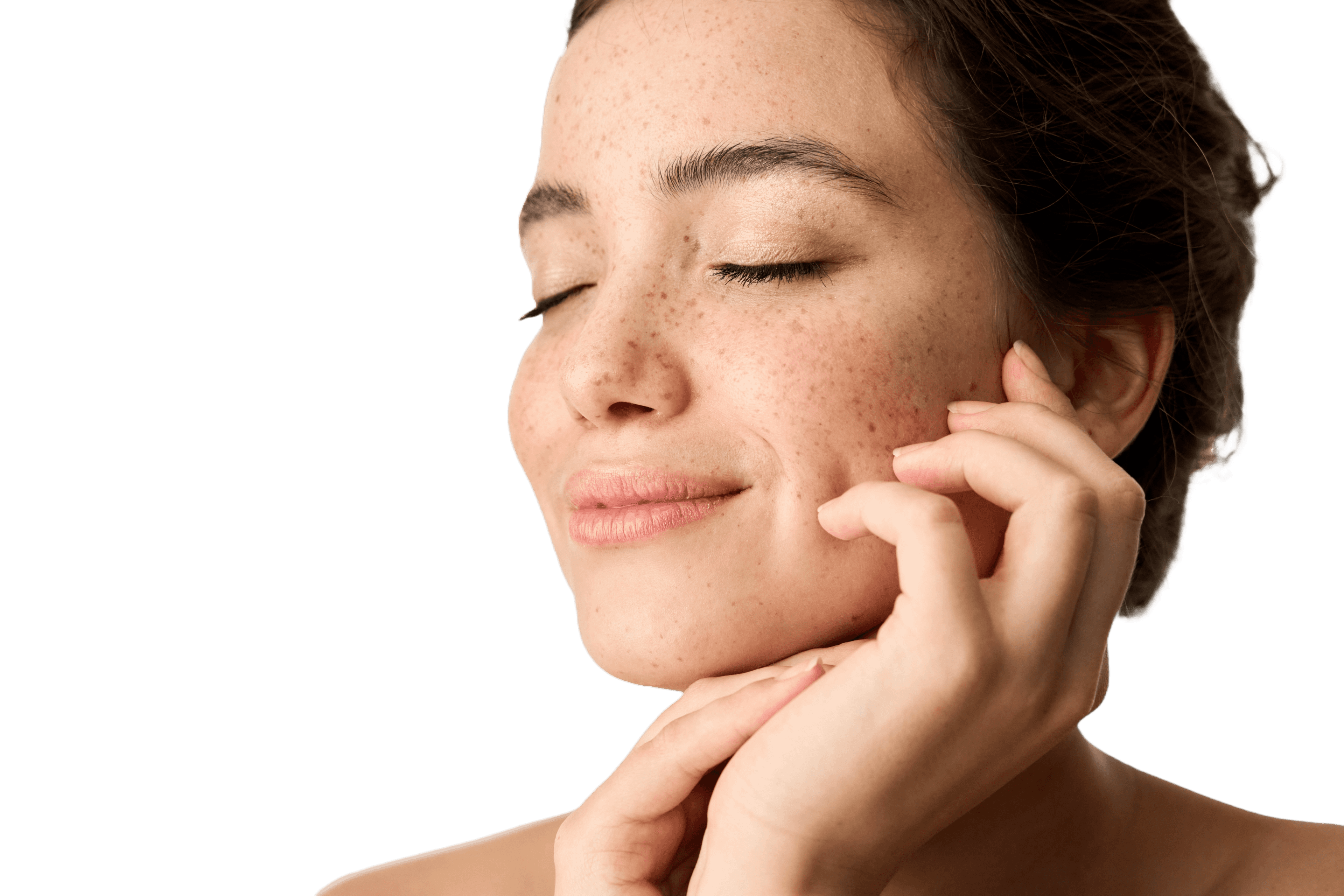 Portrét mladé ženy s pihami a zavřenýma očima – jemně se usmívá a dotýká se své tváře. Působí klidně a přirozeně a je osvícena měkkým světlem.