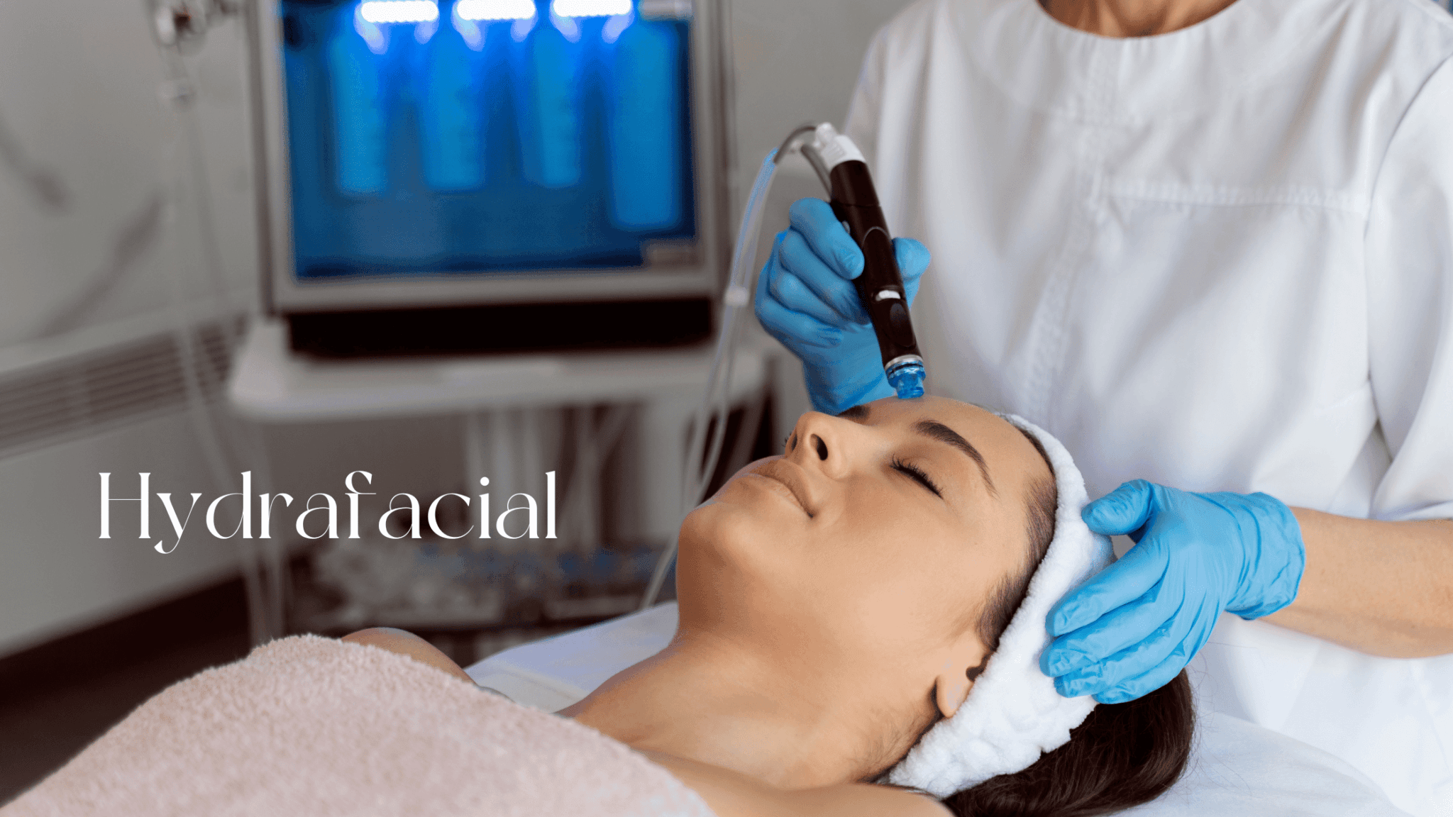 Kosmetička provádí ošetření HydraFacial na obličeji ženy ležící na lehátku, zatímco v pozadí je vidět přístroj Hydrafacial. Na fotce je text ‚Hydrafacial‘.