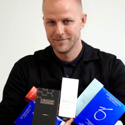 Dermatolog MUDr. Martin Bortlík drží v rukou různé produkty kosmetické péče značky ZO Skin Health a další dermatologické produkty.