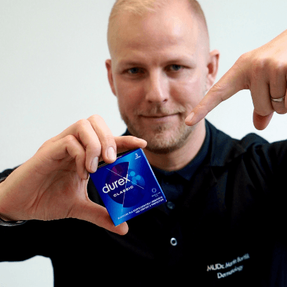 Dermatolog MUDr. Martin Bortlík drží balení kondomů a ukazuje na něj pro znázornění osvěty v oblasti screeningu pohlavních chorob.